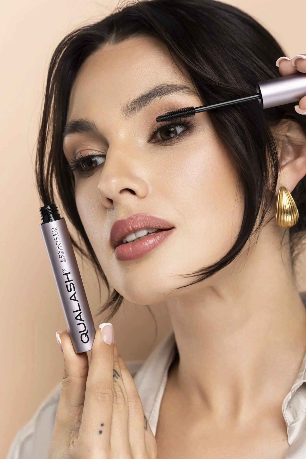 Smiling woman holding QUALASH Advanced Mascara Volume Max after application – Step 2