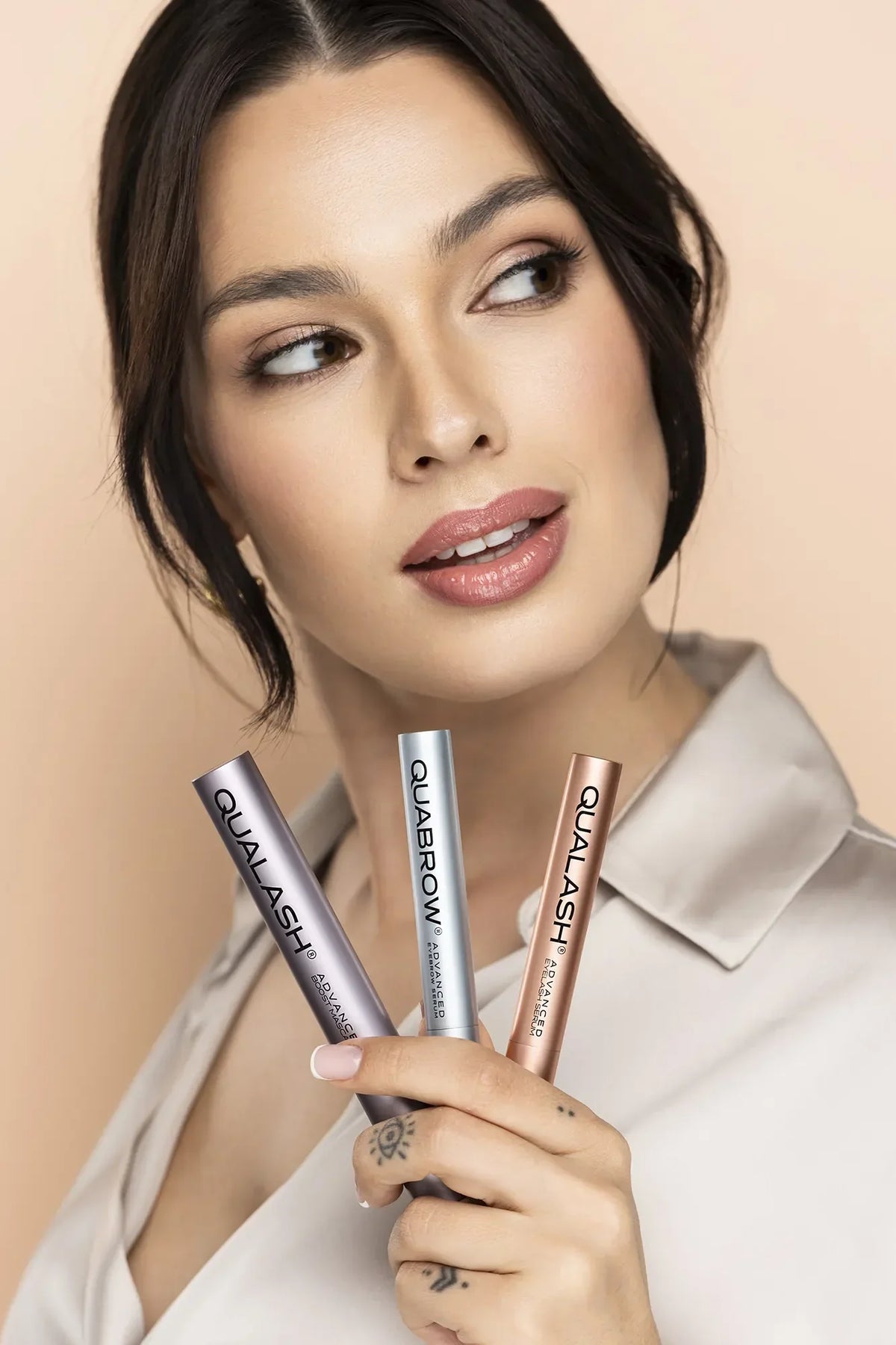 Žena držiaca tri produkty QUALASH & QUABROW čelne – starostlivosť o mihalnice a obočie