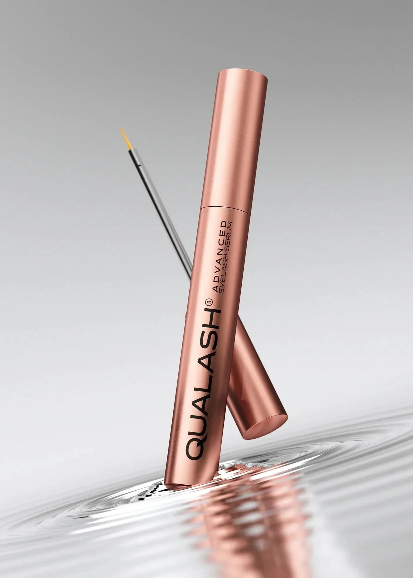 QUALASH Advanced Eyelash Serum standing in a ripple of water, silver background